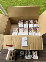 Open cardboard box containing 10 sealed RWBY Weiss Schwarz trading card booster packs and loose cards scattered outside the box.