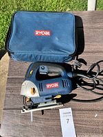 Ryobi electric jigsaw and blue Ryobi carrying case on outdoor surface