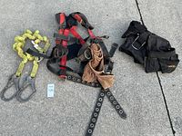 Overview of the safety harness, tool belt, and safety rope lanyard laid out on pavement.