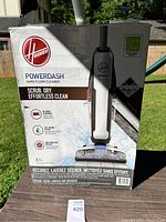Hoover PowerDash hard floor cleaner box showing branding and features like no-work scrubbing, fast-drying system, and SpinScrub brushes.