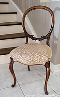 Front view of antique French ring back chair showing oval backrest, carved wood details, and patterned upholstered seat.