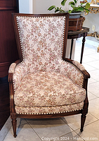 Full front view of armchair showing carved wooden frame and floral upholstery.