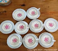 Overview of six teacup and saucer sets and a stack of six dessert plates on wooden surface