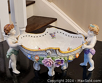 Full view of the Dresden porcelain figural bowl with two cherubs holding the bowl, detailed floral and gold trim decoration visible.