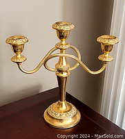 Front view of gold plated 3-arm candelabra showing decorated candle holders and curved arms.