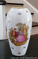 Front angle showing the romantic scene of a man and woman in historical costume, floral and gold leaf decorations on white porcelain.
