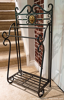 Full front angled view showing the quilt rack's structure, decorative scroll elements, and gold medallion centerpiece.