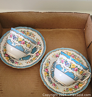 Pair of Crown Staffordshire teacups with matching saucers featuring blue and gold floral patterns.