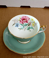 Top view of teacup inside saucer showing floral pattern inside teacup and green saucer with gold trim