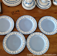 Photo showing five 8" Wedgwood blue jasperware plates with white relief grapevine pattern on the rim, arranged on wooden surface.