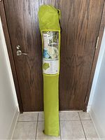 Full view of green carrying holster bag standing upright with umbrella inside, label visible on bag