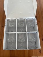 Six crystal wine glasses neatly arranged in original box with compartment dividers to keep glasses separated and secure.