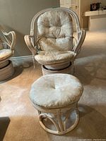 Front view of the Boca rattan swivel chair and ottoman with their cushions in cream color showing details of rattan frame and fabric.