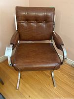 Front view of one brown vinyl upholstered chair with chrome frame showing seat, backrest with button tufting, and padded armrests.