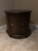 Front and side view of the round drum shape wooden end table showing two decorative front doors with metal handles.