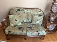 Front view of the rattan love seat with cushions showing overall condition