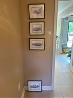 Four framed Vancouver waterfront prints arranged vertically on a wall, one print on the floor below the other three.