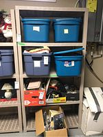 Full view of resin shelving unit with multiple blue and gray plastic storage bins and boxes placed on shelves.