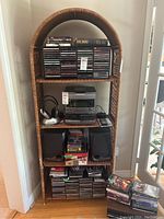 Frontal view showing wicker shelving unit with an arched top, three shelves with flat surfaces made of wicker material.