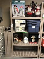 Fully assembled resin shelving unit with various holiday decorations and several boxes on shelves.