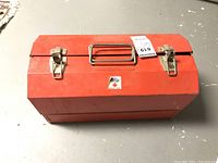 Closed red metal toolbox with two latches and handle on top. Flaherty Hamilton Canada label visible on front.