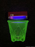 Top view of the green vaseline glass mixing bowl glowing under UV light to show fluorescent properties.