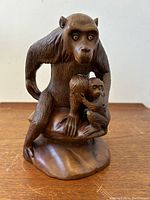 Front view showing adult monkey with baby simian clinging to chest, detailed fur carving, and glass eyes.