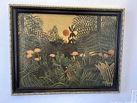 Front view of framed Henri Rousseau art print showing jungle scene with flowers, foliage, and sun or moon.
