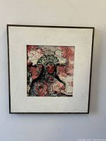 Frontal view of impressionist oil painting depicting a woman in headdress with pink/red background, in frame with white textured mat.