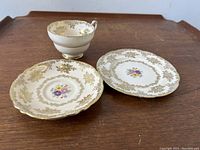 Tea cup, saucer, and side plate trio shown full view on wooden surface, illustrating size and design.