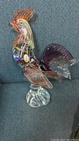 Side view of Murano glass rooster figurine showing label and colorful internal detail