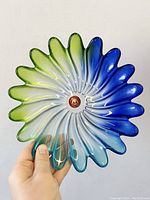 Front view showing the green to blue gradient fluted swirl art glass bowl held in hand to display shape and color.