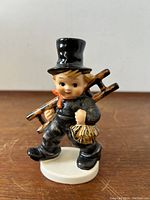 Front view of the chimney sweep boy figurine showing the painted details and top hat.