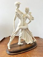 Front angled view showing the detailed male and female dancers in a dancing pose on wooden base.