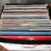 Box of LP records viewed from the top, showing the edges and spines of many albums stacked upright inside a cardboard box.