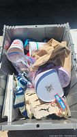 Photo of storage bin contents showing assorted cups, paper bag, plastic container and other misc items