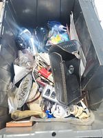 Photo showing assorted items including a vintage leather case, bird figurine, various hand tools and parts inside a large plastic bin.