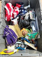 Top view of bin showing folded U.S. flag, purple velvet bag, various toys, and miscellaneous vintage items inside a gray plastic bin.
