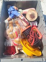Bin with assorted dolls, plush reindeer toy, Coca-Cola cup and lid, and other assorted items