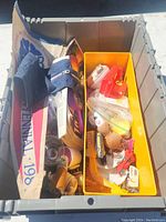 Wide view inside storage bin showing grouped items including toys, fabric pennants, and small glassware