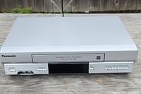 Front view of Panasonic VCR showing the power button, channel control arrows, and other functional buttons along with display screen.