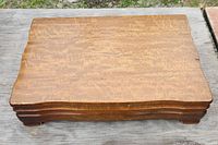 Closed wooden box with polished finish and curved top edges.