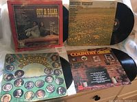 Four vinyl records and album covers showing front with artist images and titles.