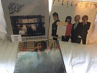 Photo of three sealed vinyl albums displayed upright: The Rare Occasions, The Pretenders, and Eric Clapton's Slowhand.