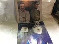 Photo showing two vinyl records: Sandler's Cottonfields Spanish Eyes and Annette Ducharme album, displayed side-by-side on a white cloth backdrop.