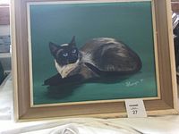 Framed painting showing a Siamese cat on green background with artist signature and date