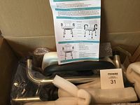 Photo of bath bench parts packed in the box with assembly instructions visible