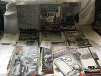 Multiple QST magazines and books about amateur radio, laid out on a flat surface showing front covers and some spines