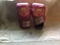 Pair of Venum pink boxing gloves standing upright showing front with logo and Velcro closure.
