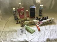 Photo showing 10 assorted cosmetic and fragrance items on a fabric background with seller lot card 76 visible.